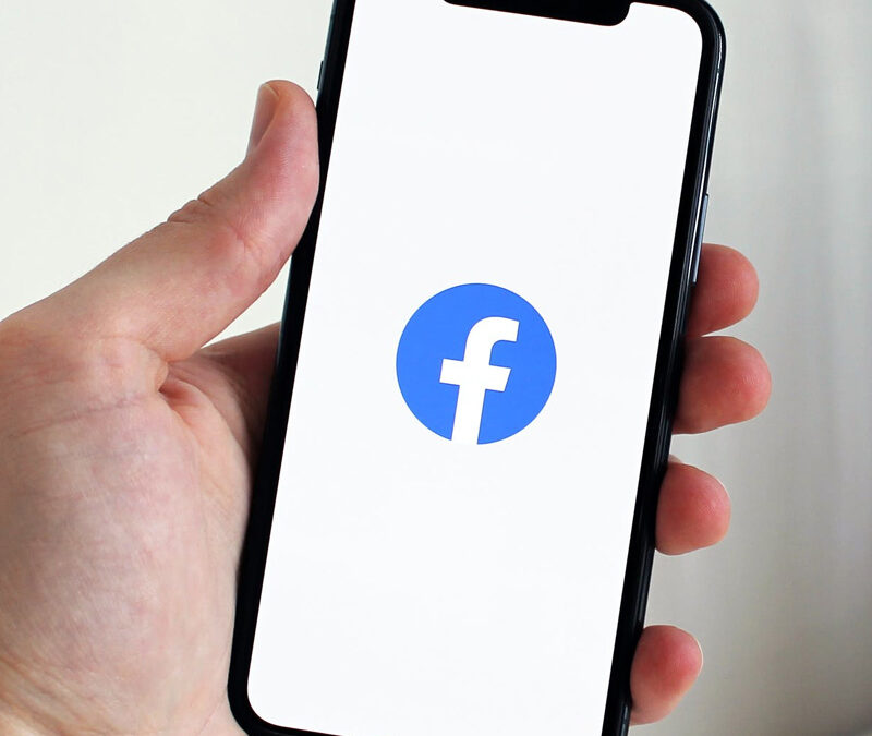 Utente che gestisce la pagina aziendale su Facebook Business Suite dal laptop, monitorando statistiche e programmando post.